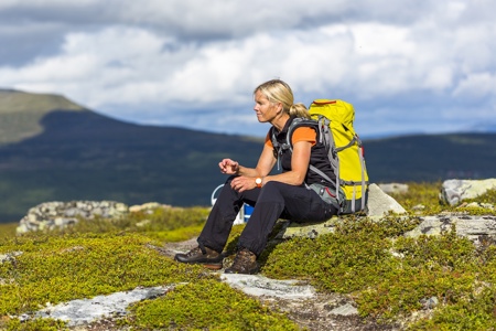 Kvinna på fjällvandring tar en paus på en sten